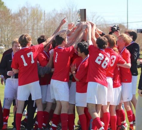 Team celebrates 7th consecutive state championship as they hoist the trophy above. Photo by Stewart McCullough.