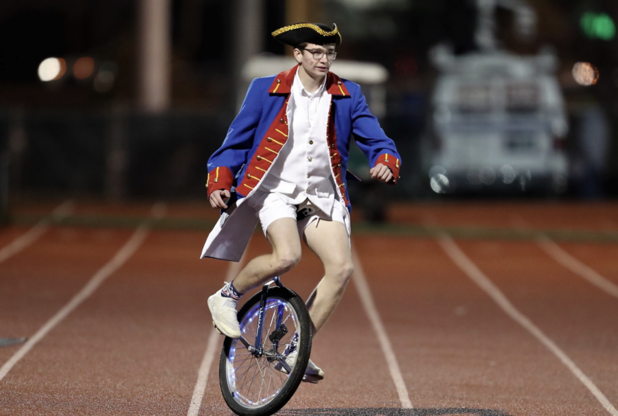 Ben Johnson, the Patriot Man, unicicles down the track to support the football team.
