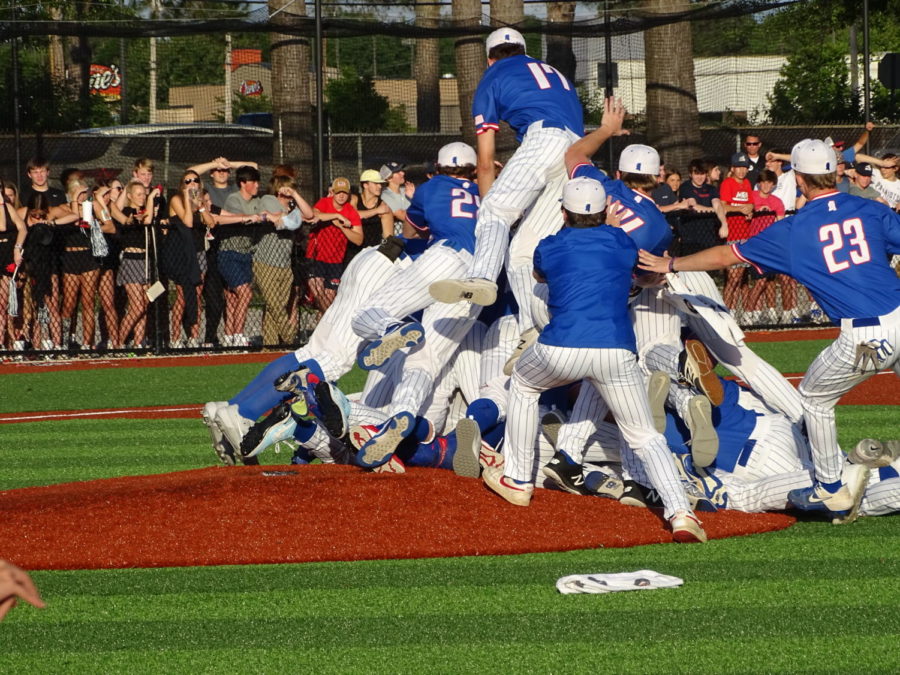 The team rushes the field, creating a dog pile on top of Will Gibbs, the closing pitcher, after the final out of the championship series.  